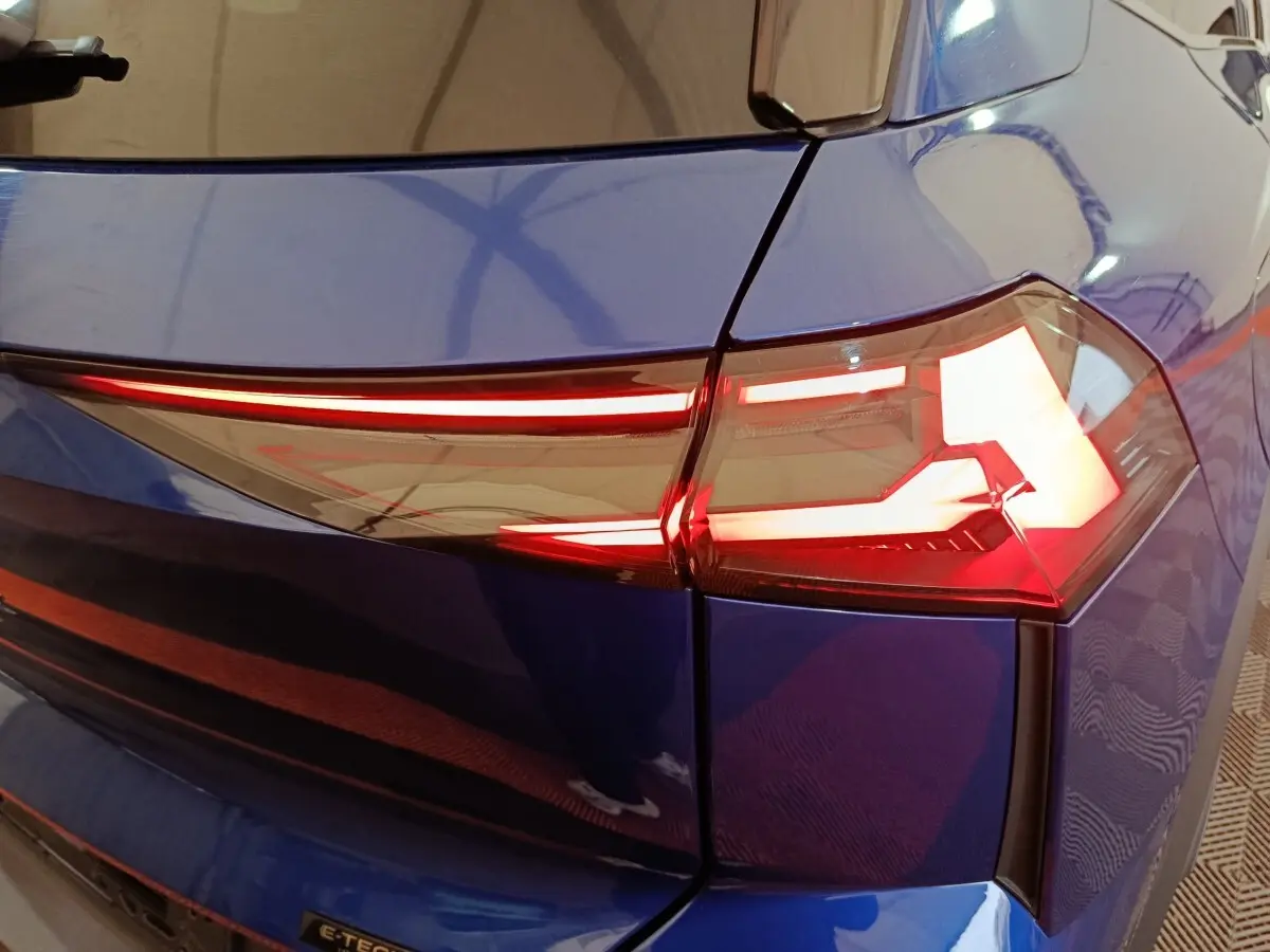 Feu arrière droit allumé sur Renault Symbioz bleu, vue rapprochée du coin arrière du véhicule.