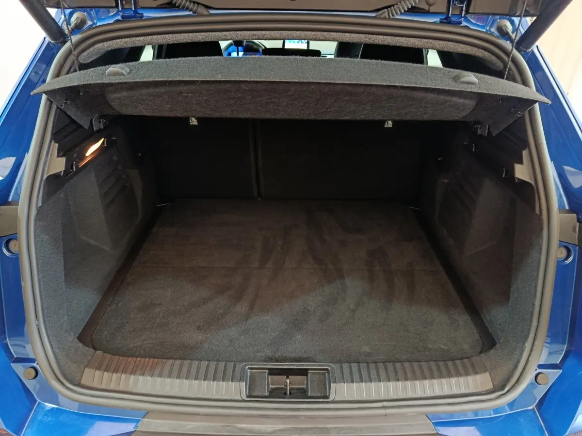 Coffre ouvert vu de l'arrière d'une Renault Symbioz bleu, montrant un espace de chargement propre et spacieux.