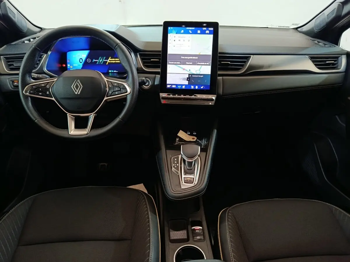 Vue intérieure avant du tableau de bord noir de la Renault Symbioz 2025 avec écran tactile central vertical et volant multifonction.