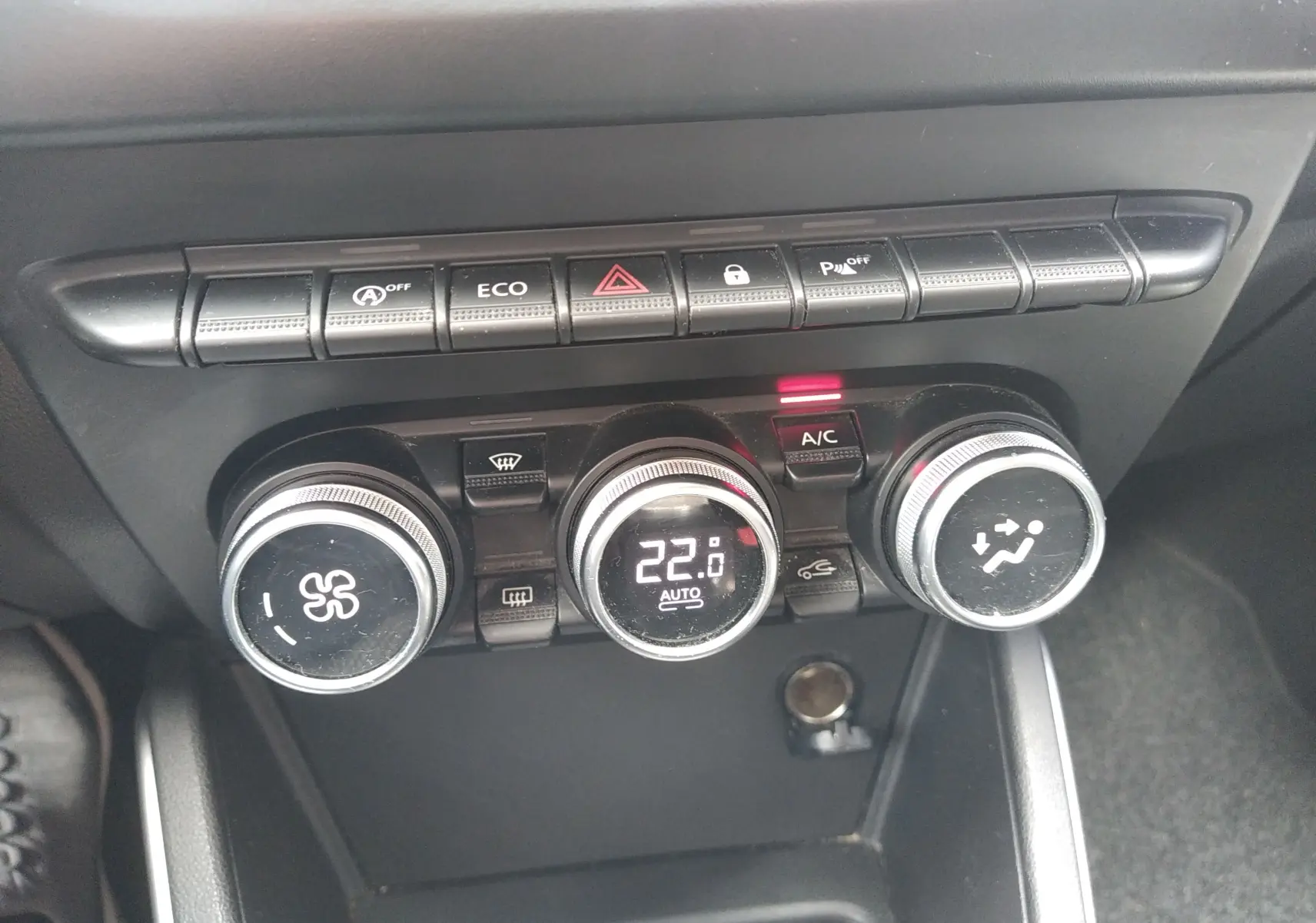 Gros plan sur les commandes de climatisation et les boutons de fonction du tableau de bord du Dacia Duster gris 2020.