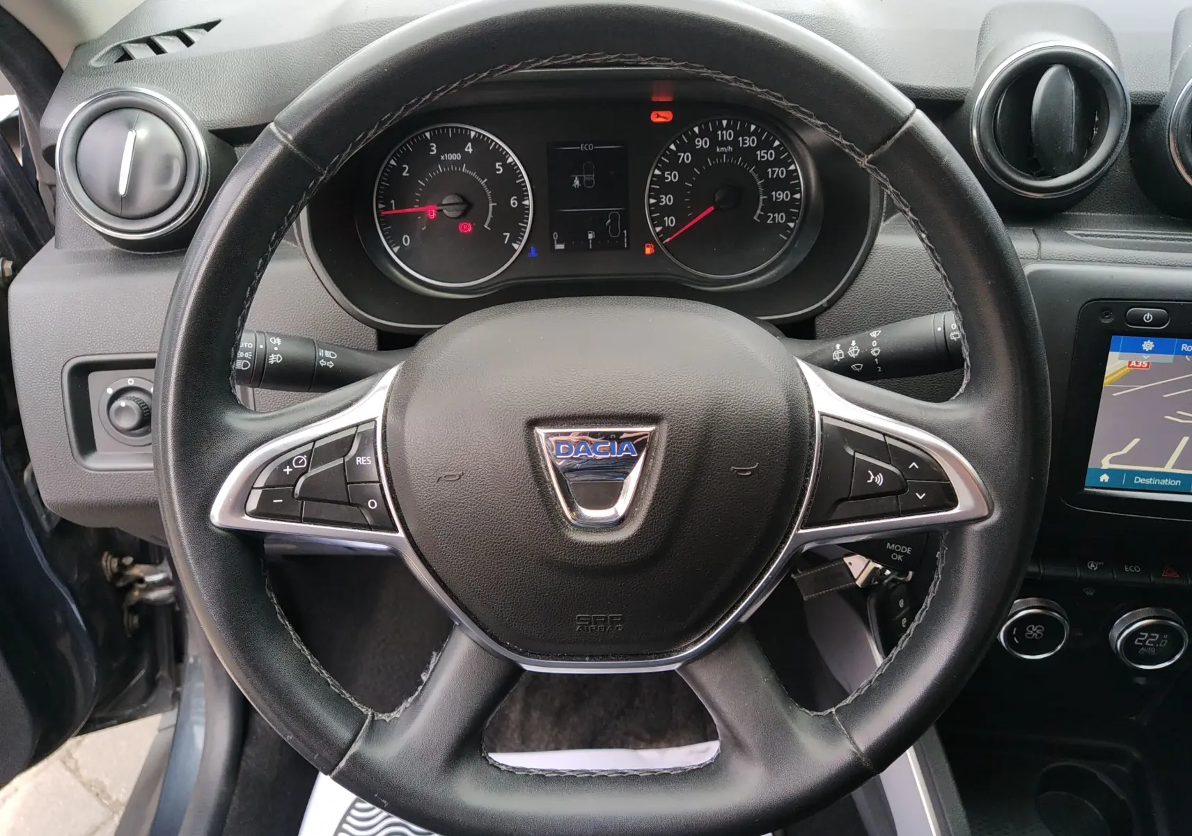 Vue rapprochée du volant noir du Dacia Duster 2020 avec tableau de bord et écran GPS visible à droite.