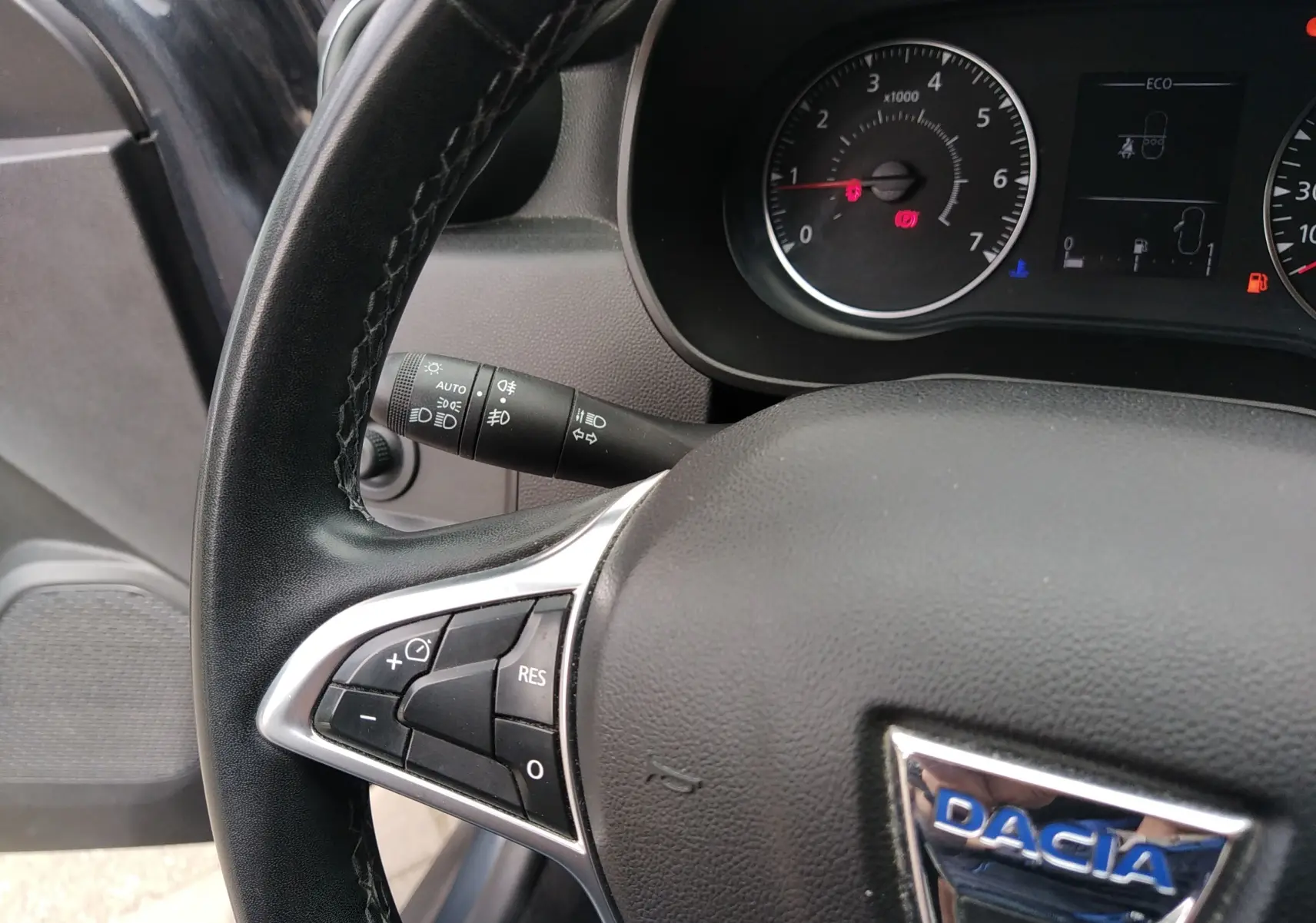 Gros plan sur le volant noir du Dacia Duster 2020, avec commandes intégrées et tableau de bord partiellement visible.