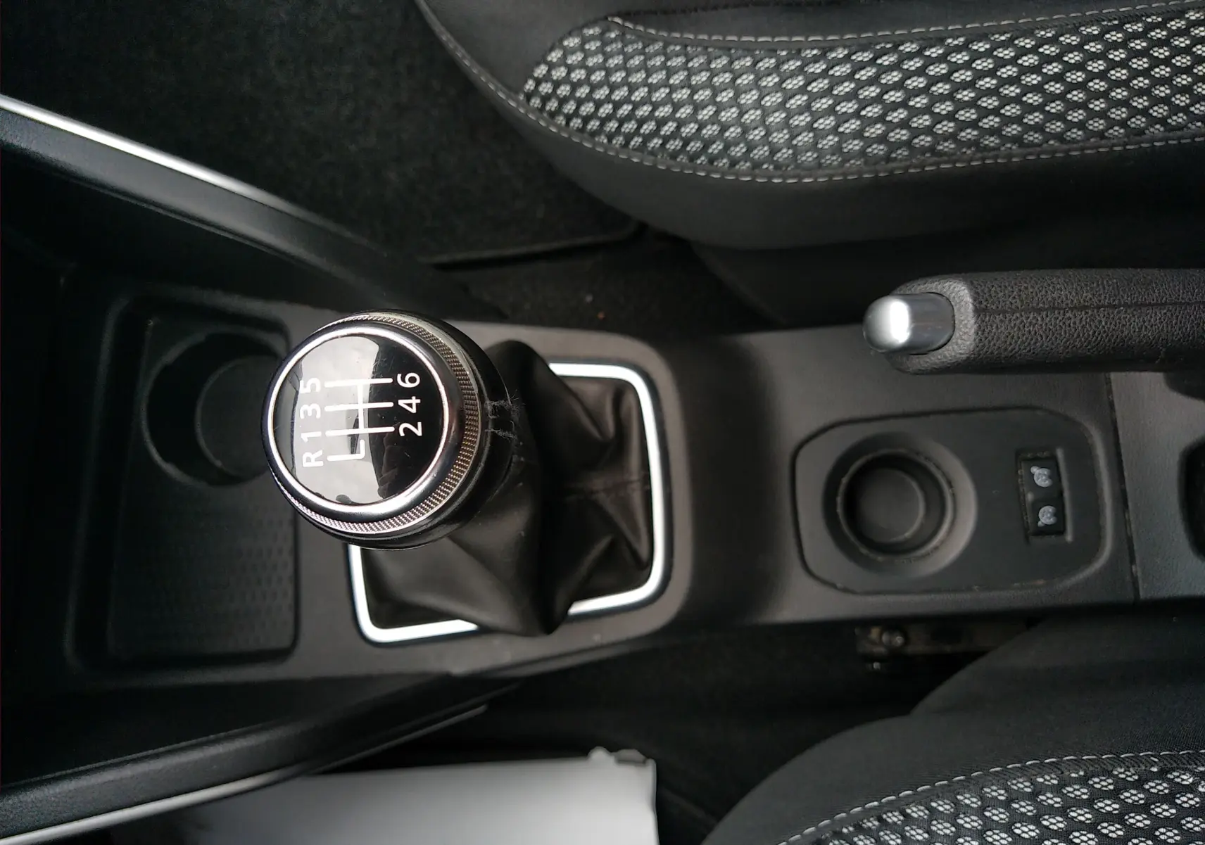 Vue rapprochée du levier de vitesses manuel et frein à main du Dacia Duster 2020, intérieur tissu noir à motifs.
