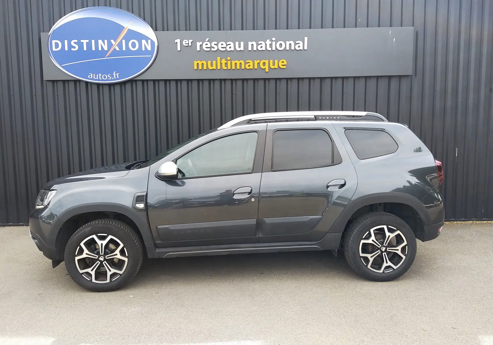 Profil côté gauche d'un Dacia Duster gris 2020, finition Prestige, avec jantes alliage noires et toit argenté.