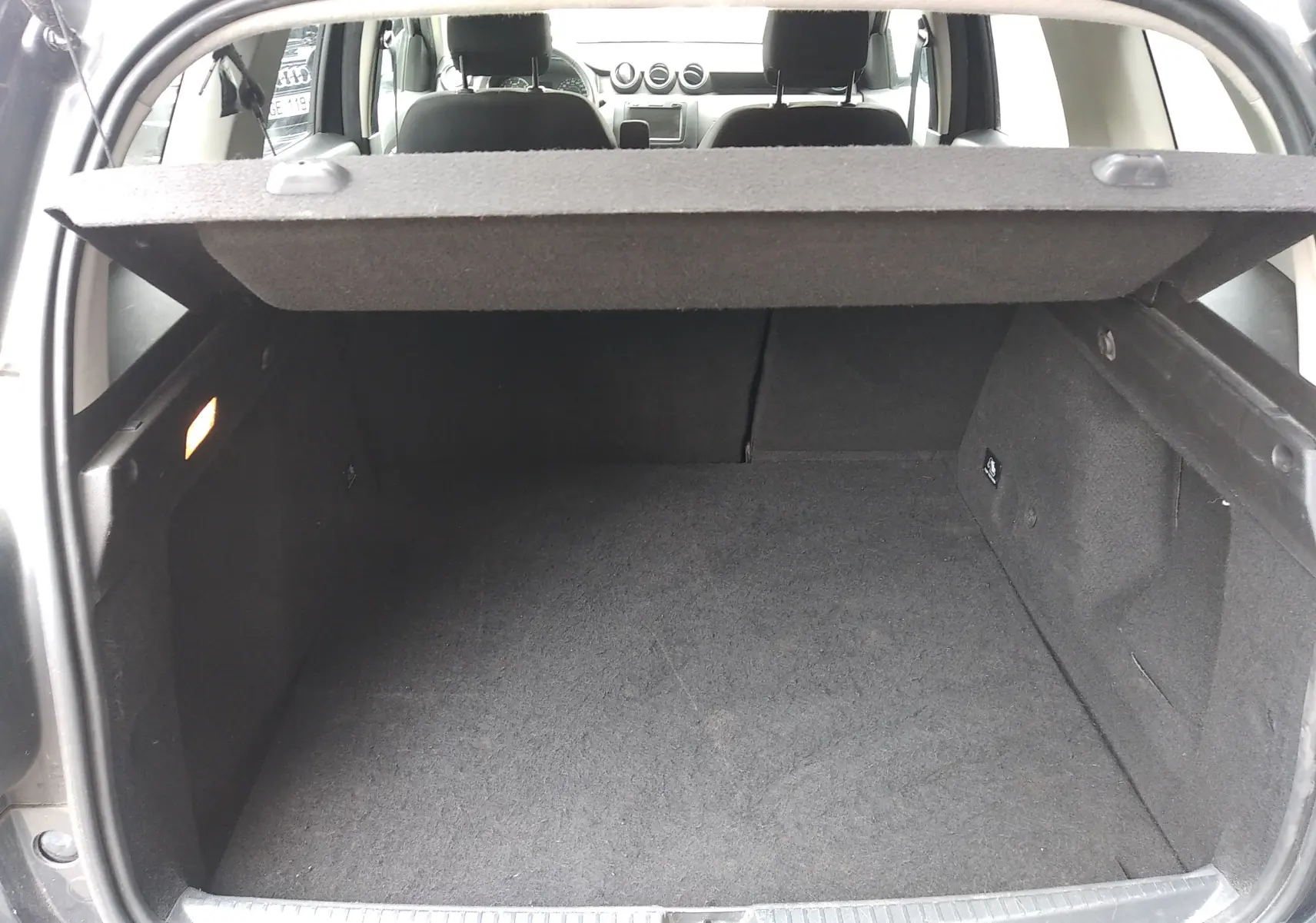 Coffre ouvert d'un Dacia Duster gris 2020, vue intérieure arrière montrant l'espace de chargement et la tablette cache-bagages.