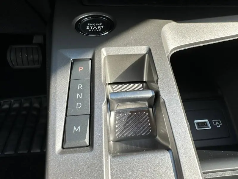 Vue rapprochée de la console centrale grise avec bouton start/stop et commandes de boîte automatique de la Peugeot 308 2025.