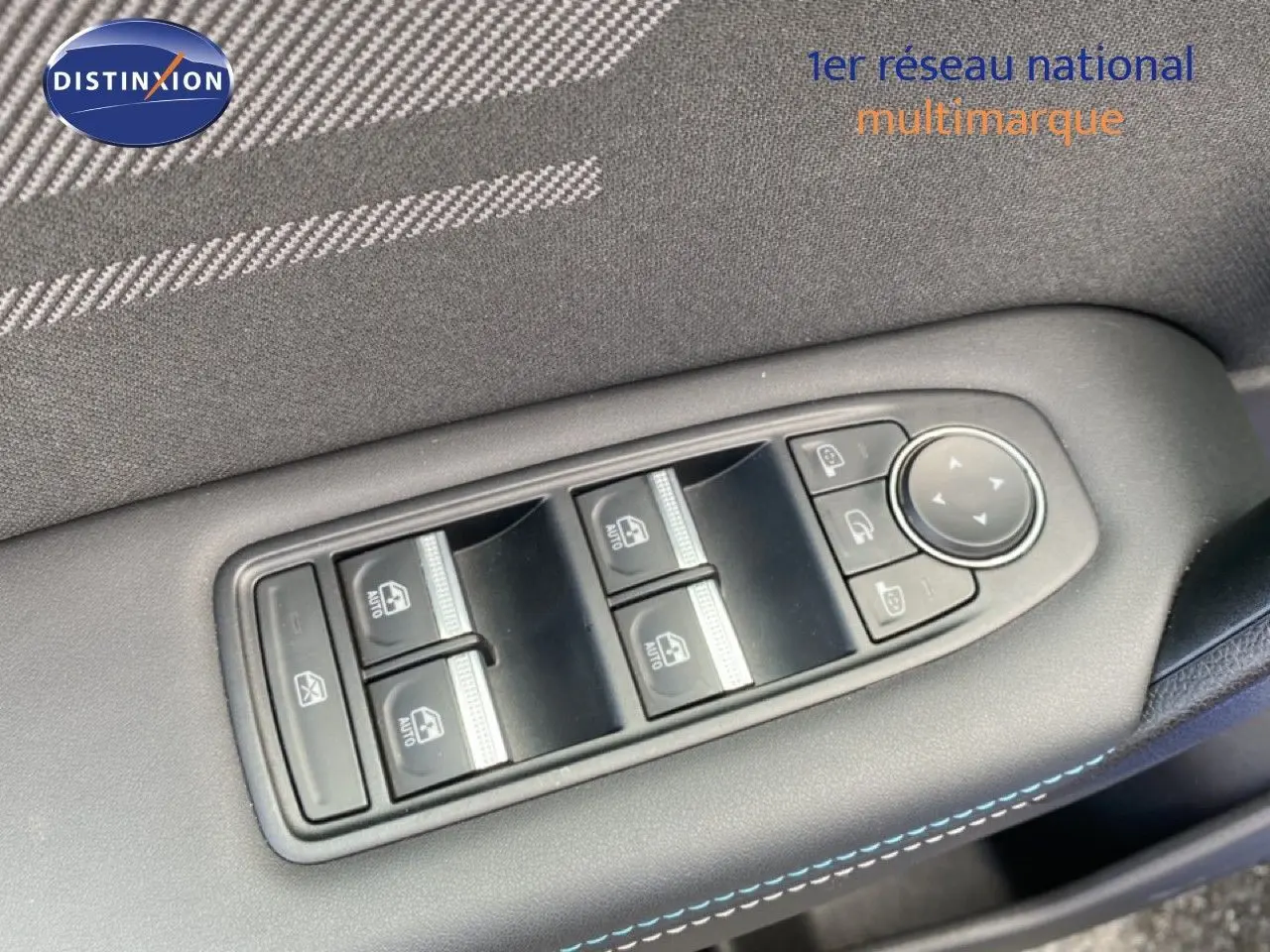 Gros plan sur les commandes de lève-vitres et rétroviseurs côté conducteur d’une Renault Symbioz bleu Iron Metal.