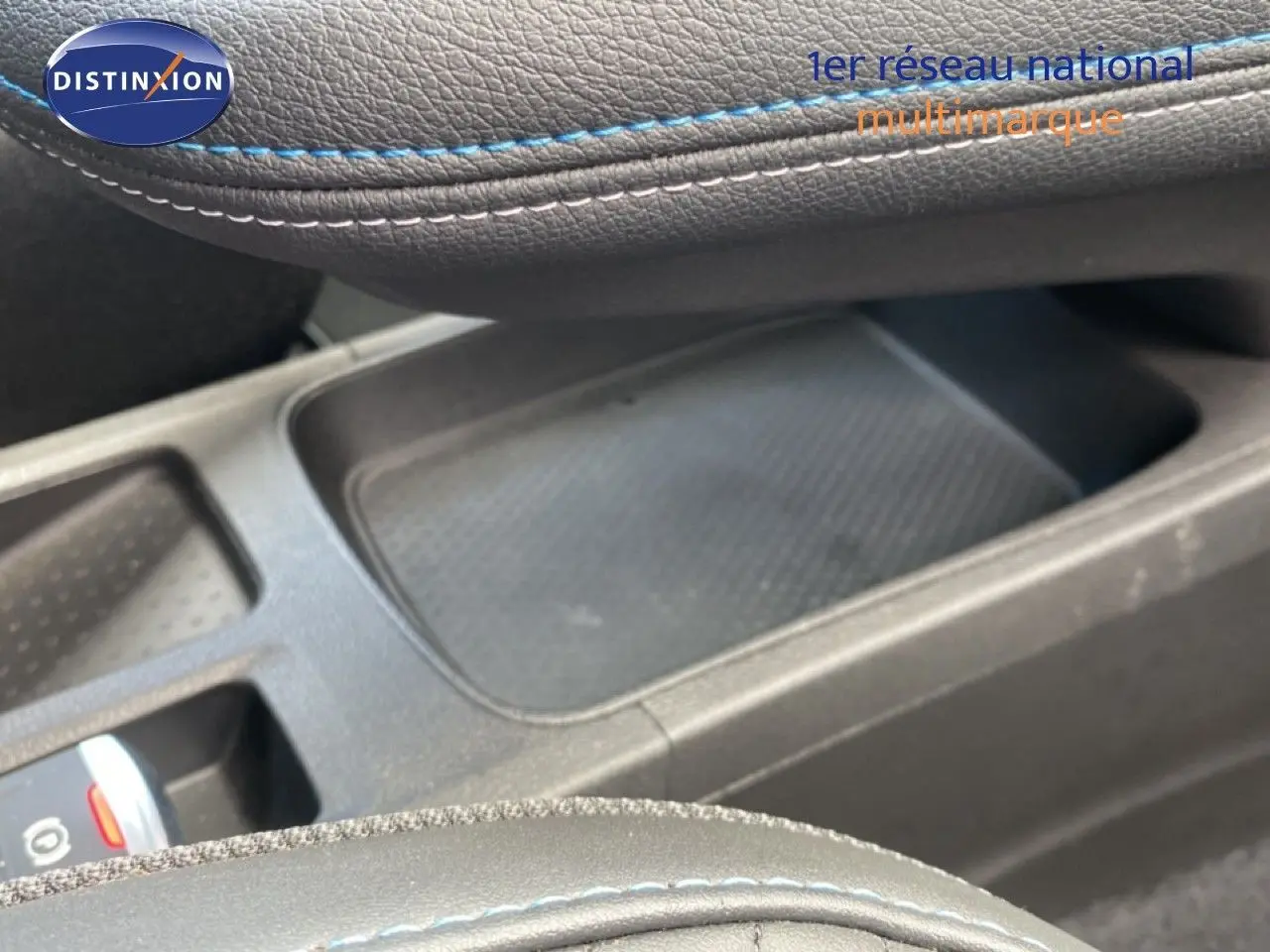 Gros plan sur la console centrale et accoudoir en cuir noir avec surpiqûres bleues du Renault Symbioz E-Tech hybride 2025.
