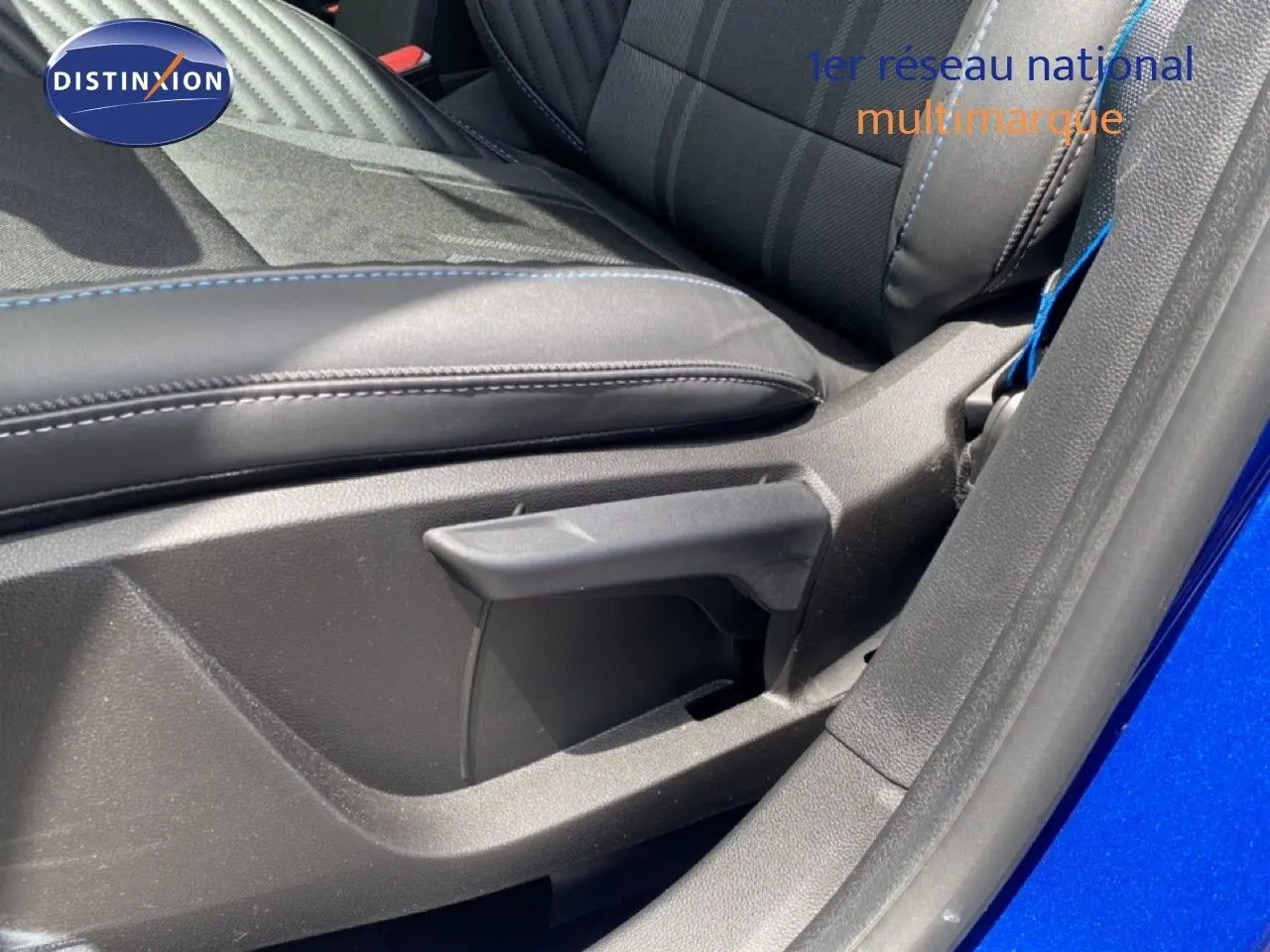 Détail de l'intérieur côté siège avant droit d'une Renault Symbioz bleu iron metal, avec sellerie noire et surpiqûres bleues.