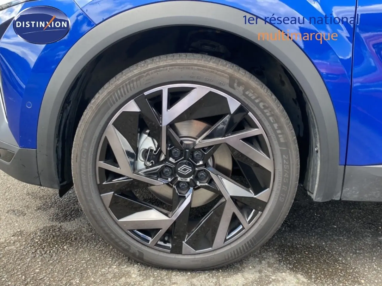 Gros plan sur la roue avant droite du Renault Symbioz bleu iron metal avec jante alliage au design géométrique.