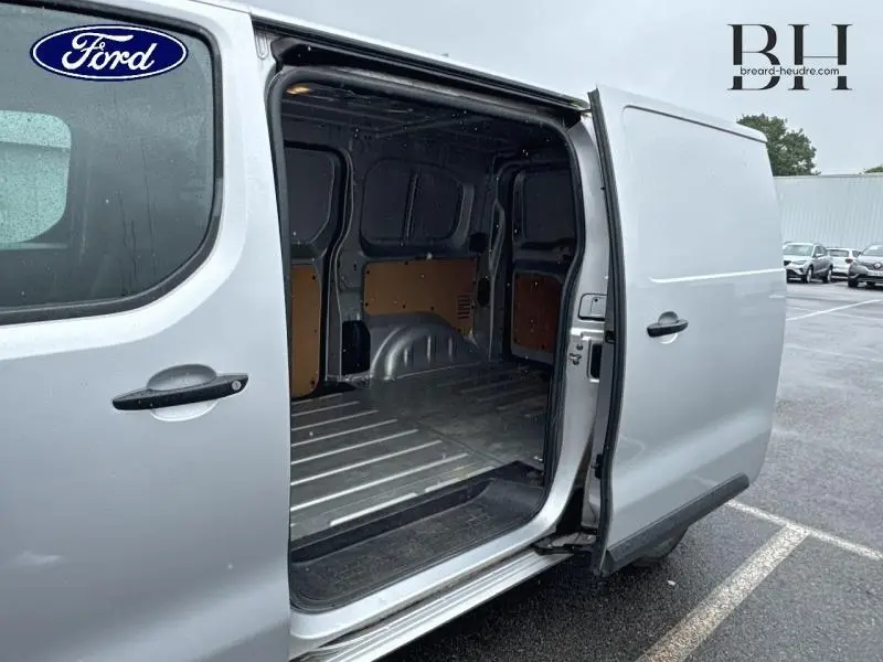 Vue latérale droite d’un utilitaire gris aluminium avec porte coulissante ouverte montrant l’espace de chargement vide.