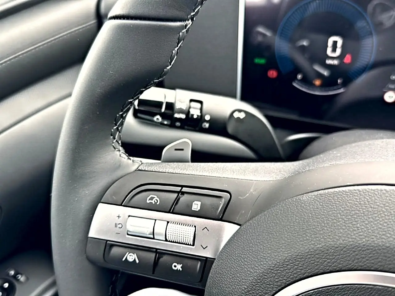 Gros plan sur le volant cuir multifonction noir du Hyundai Tucson 2026 avec commandes intégrées et tableau de bord numérique.