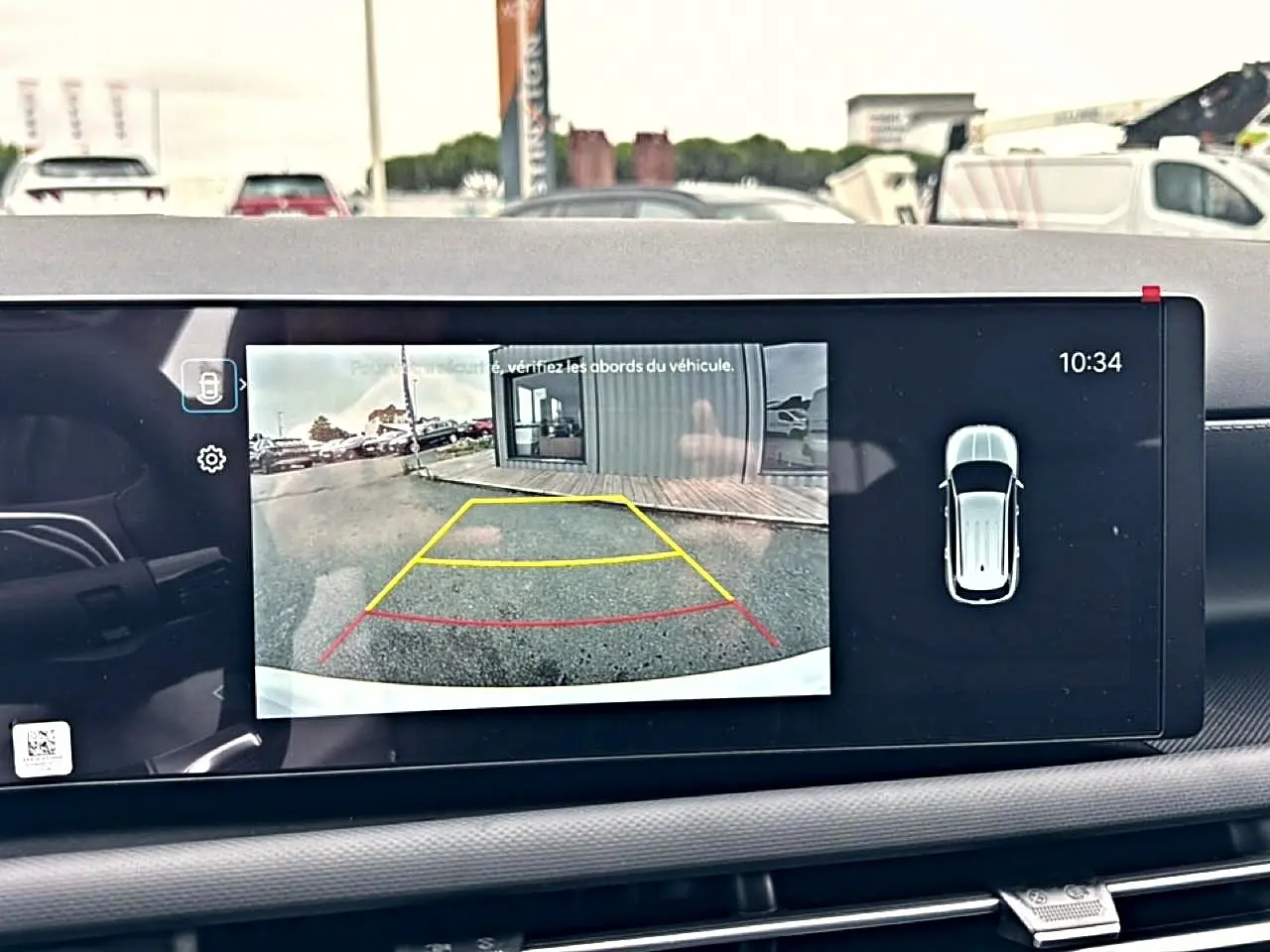 Écran intérieur montrant la caméra de recul du Hyundai Tucson blanc, vue arrière avec lignes de guidage colorées.