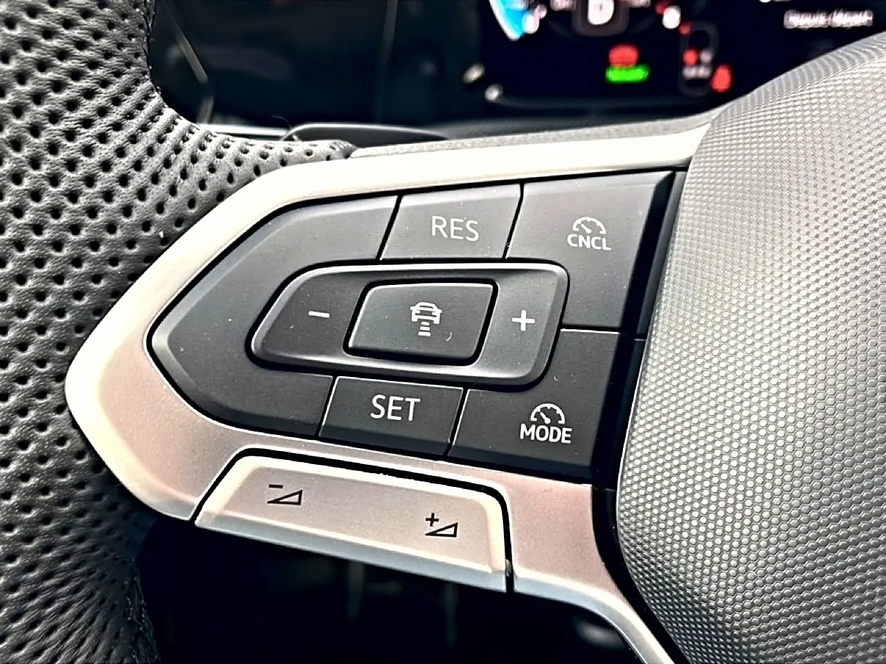 Gros plan sur les commandes multifonctions gauche du volant noir perforé de la Volkswagen Golf 2026 R-Line.