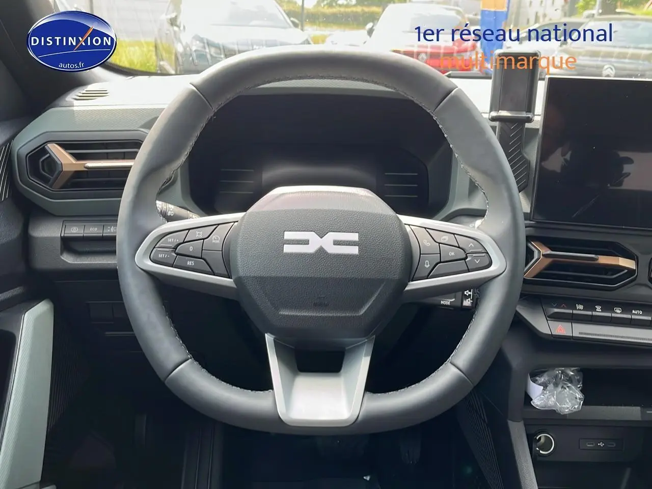 Vue centrée sur le volant multifonction noir du Dacia Duster 2025 avec tableau de bord et écran tactile visible.