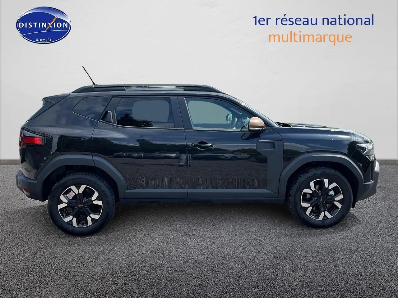 Profil côté gauche du Dacia Duster noir 2025 avec jantes alu et barres de toit visibles sur fond neutre.