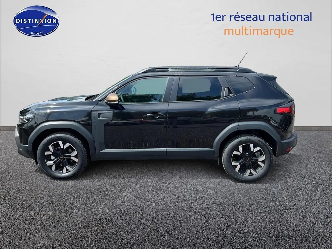 Profil côté gauche du Dacia Duster noir 2025 avec jantes alu et rétroviseur couleur bronze.