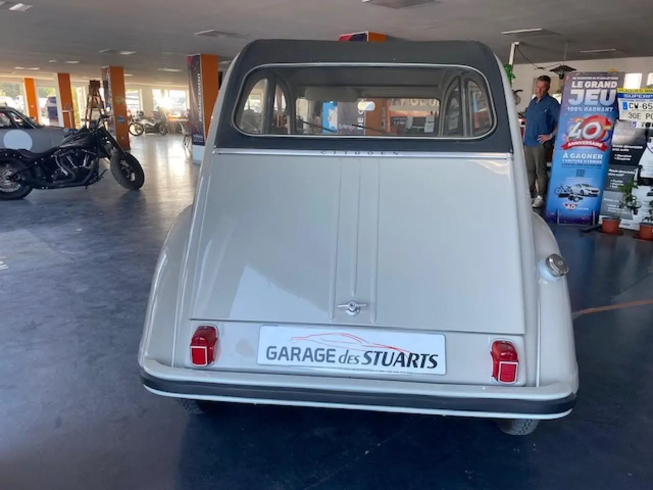 Vue arrière d'une Citroën 2 CV beige clair de 1968 refaite à neuf, avec feux rouges et toit ouvrant visible.