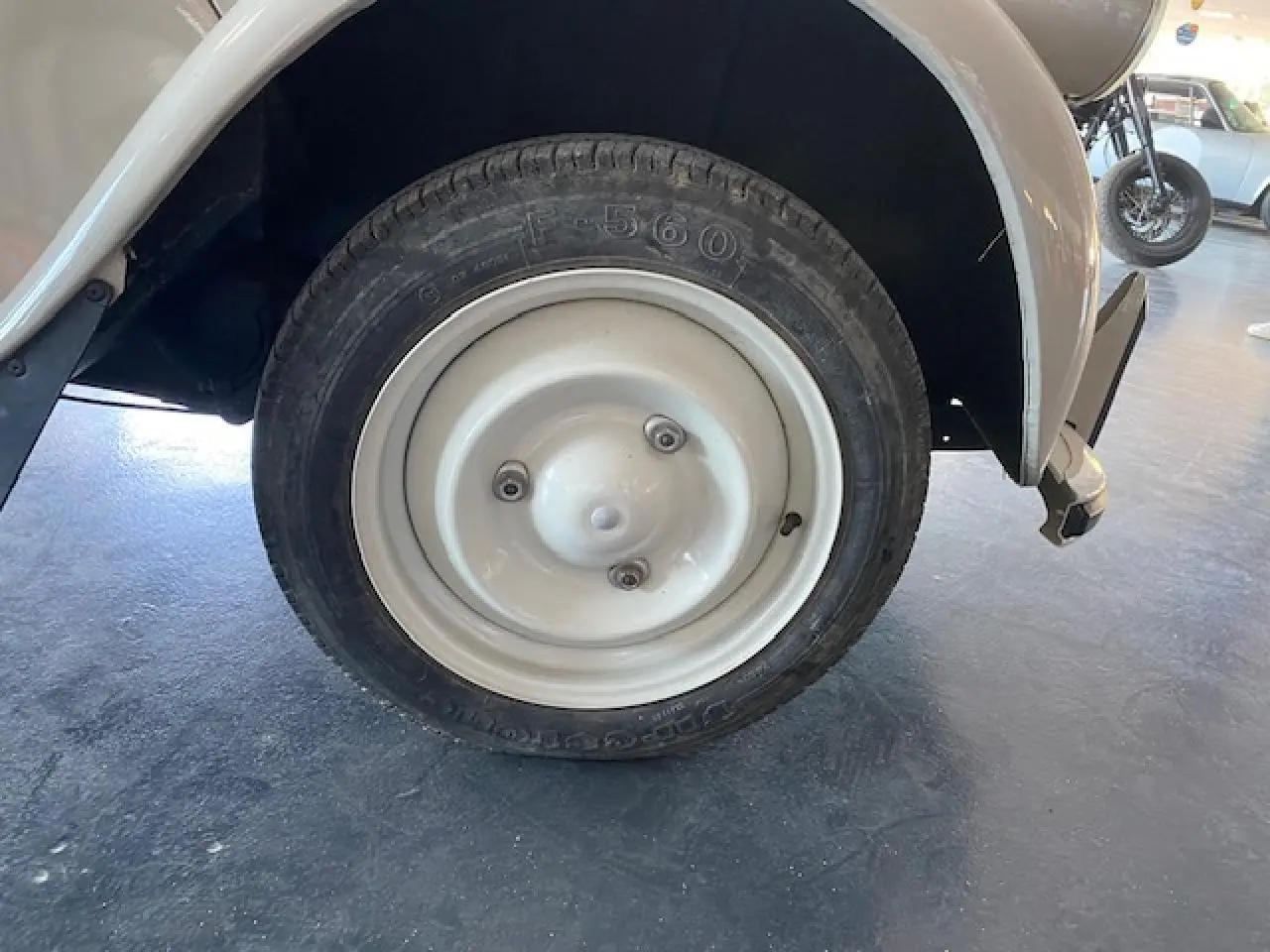 Gros plan sur la roue arrière droite beige clair d'une Citroën 2 CV 1968 refaite à neuf, avec jante métallique simple.