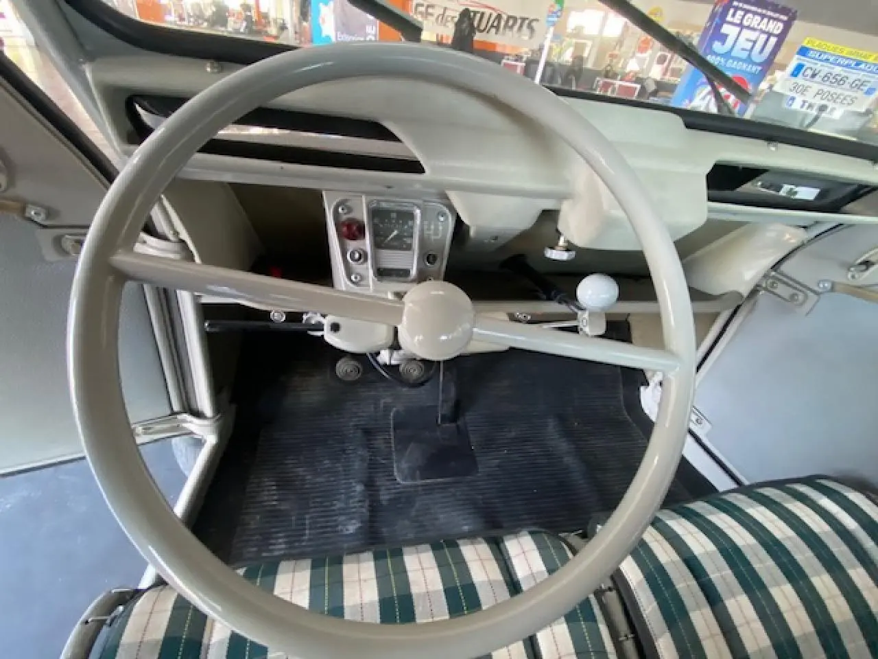 Vue intérieure centrée sur le volant beige clair et le tableau de bord minimaliste de la Citroën 2 CV 1968 rénovée.