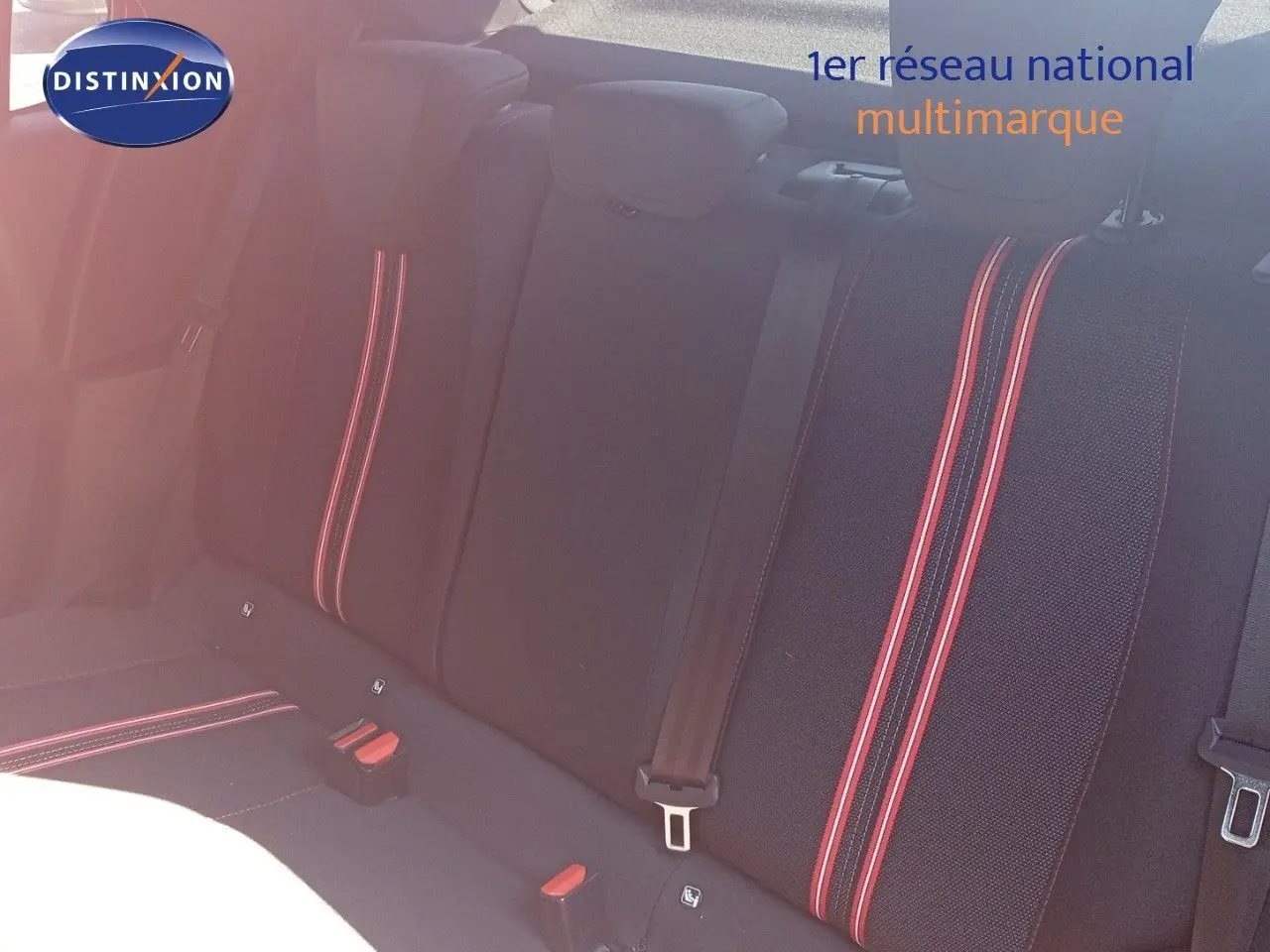 Vue intérieure des sièges arrière noirs de l'Opel Corsa 2023 avec surpiqûres rouges et ceintures de sécurité visibles.