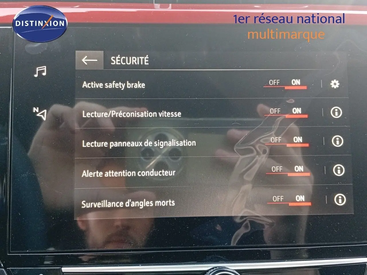 Écran tactile du système de sécurité d'une Opel Corsa rouge Kardio métal avec toit noir, affichant les options activées.