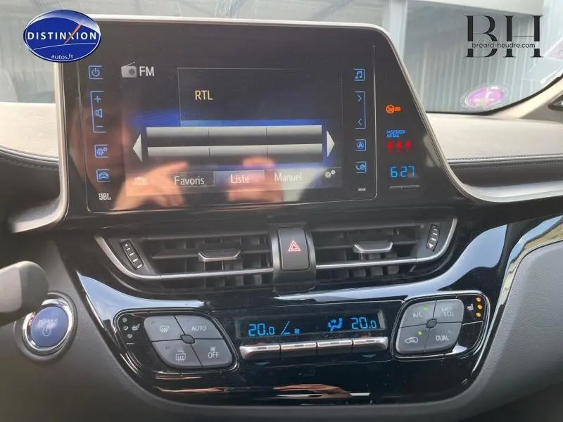 Tableau de bord du Toyota C-HR 122h blanc nacré, avec écran tactile et commandes climatisation digitales visibles.