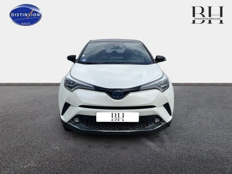 Vue avant d'un Toyota C-HR 122h Collection blanc nacré bi-ton avec phares LED et calandre noire distinctive.