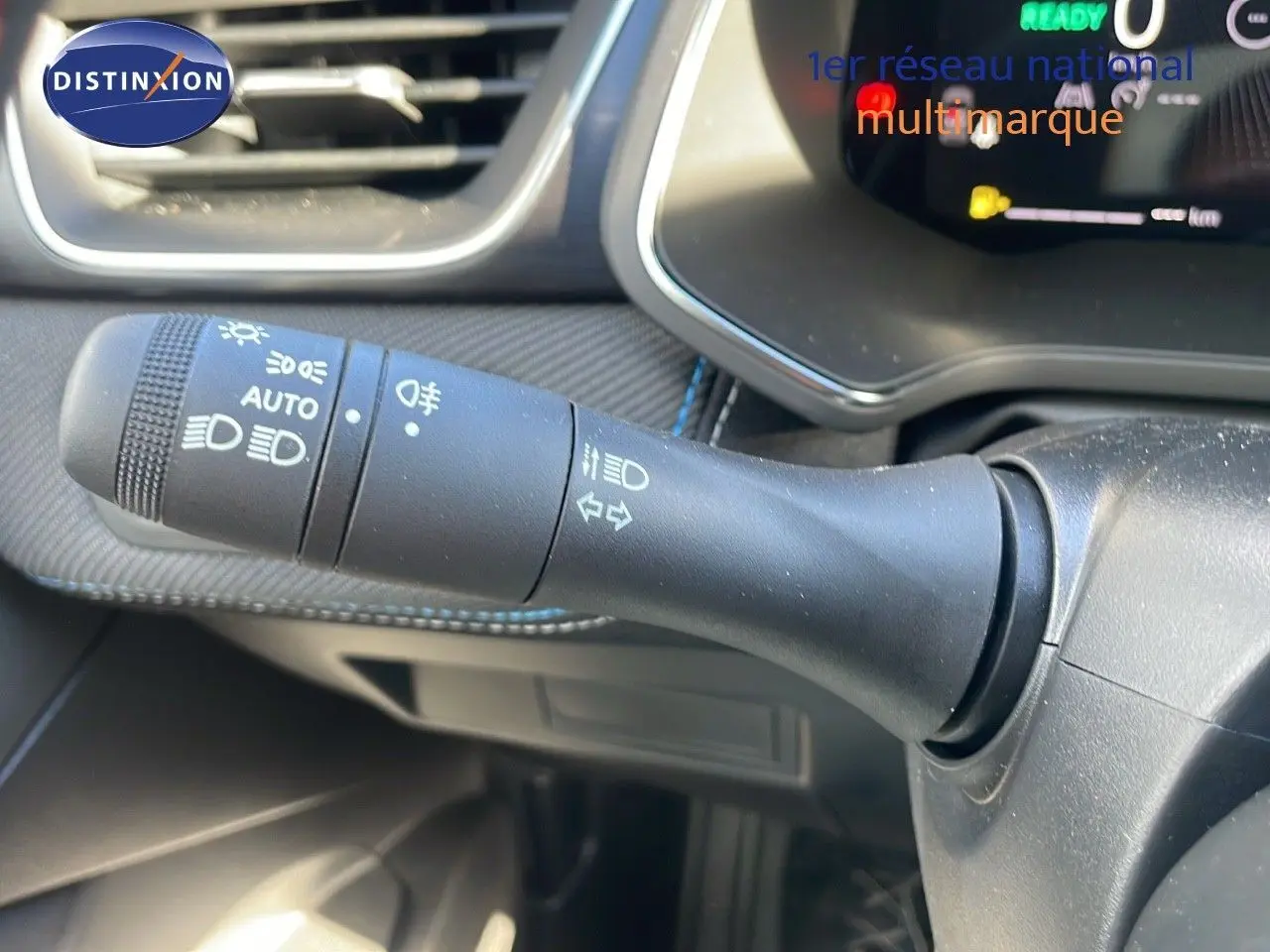 Gros plan sur la commande des phares et clignotants du Renault Captur E-Tech gris Rafale, intérieur noir avec tableau de bord numérique.