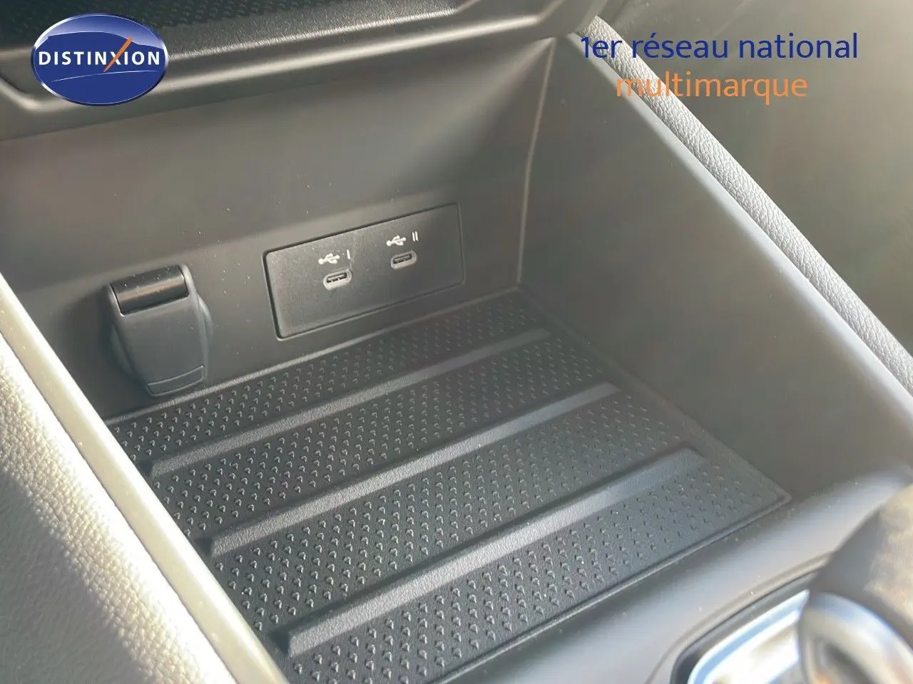 Gros plan sur la console centrale du Renault Captur E-Tech hybride 2025 montrant les ports USB et un espace de rangement noir.