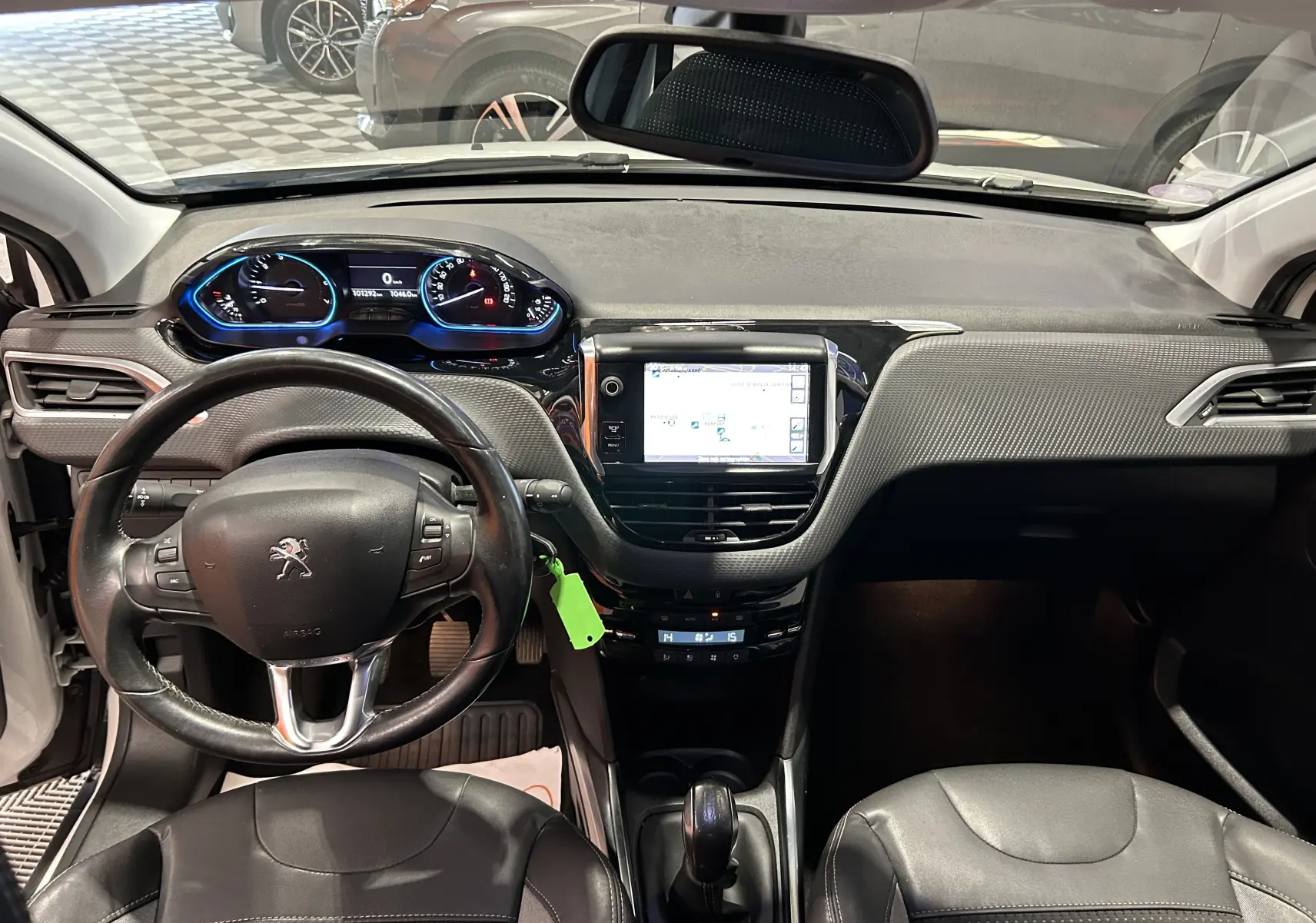 Vue intérieure avant du tableau de bord de la Peugeot 2008 blanc, avec volant cuir et écran GPS central allumé.