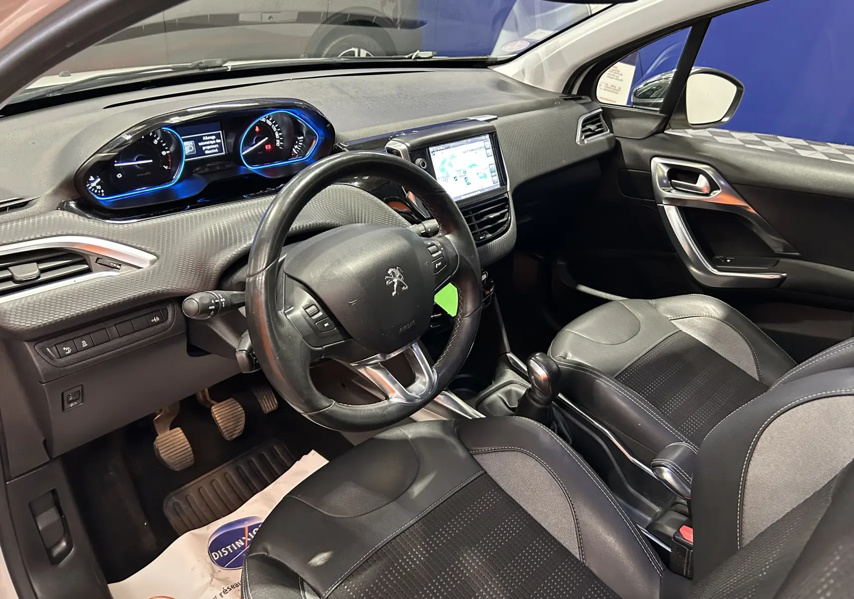 Vue intérieure côté conducteur du Peugeot 2008 blanc de 2014, avec tableau de bord et écran GPS lumineux.