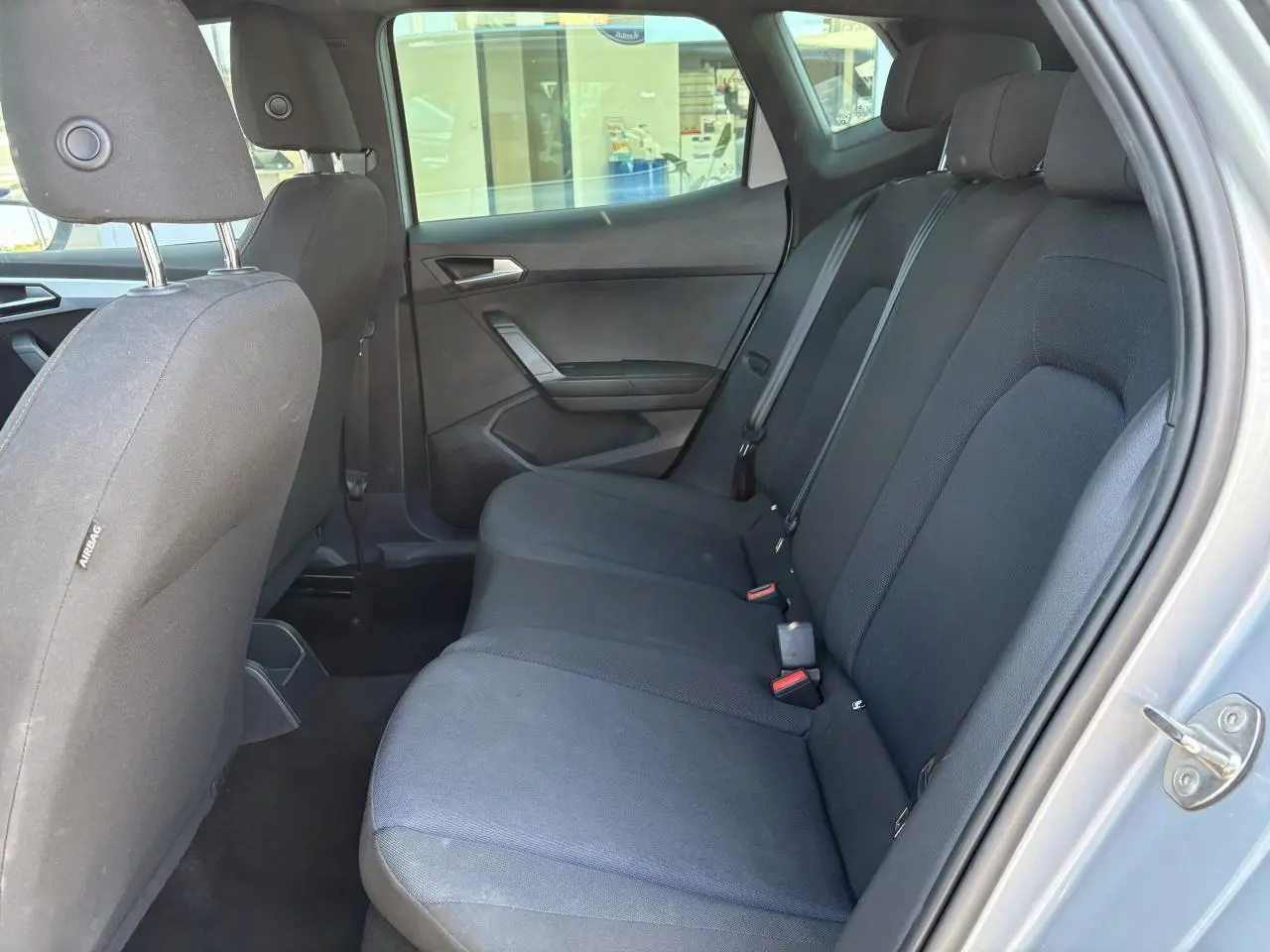 Vue latérale droite de l'habitacle arrière du SEAT Arona 2024 en gris, avec banquette textile noire et appuie-têtes.