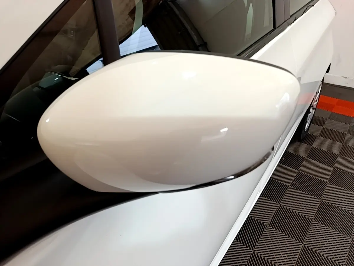 Gros plan sur le rétroviseur côté gauche d'une Renault ZOE Business R110 blanc, avec partie latérale visible.