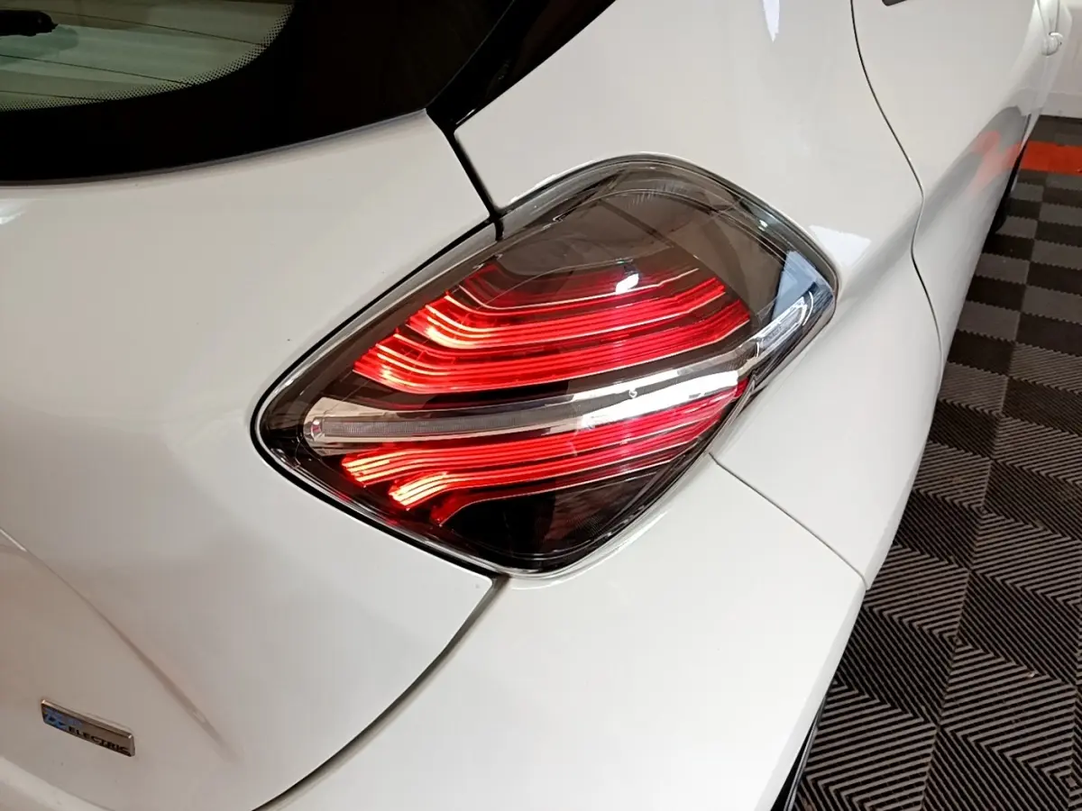 Gros plan sur le feu arrière droit rouge d’une Renault ZOE blanche, version électrique de 2021, sur sol à damier.