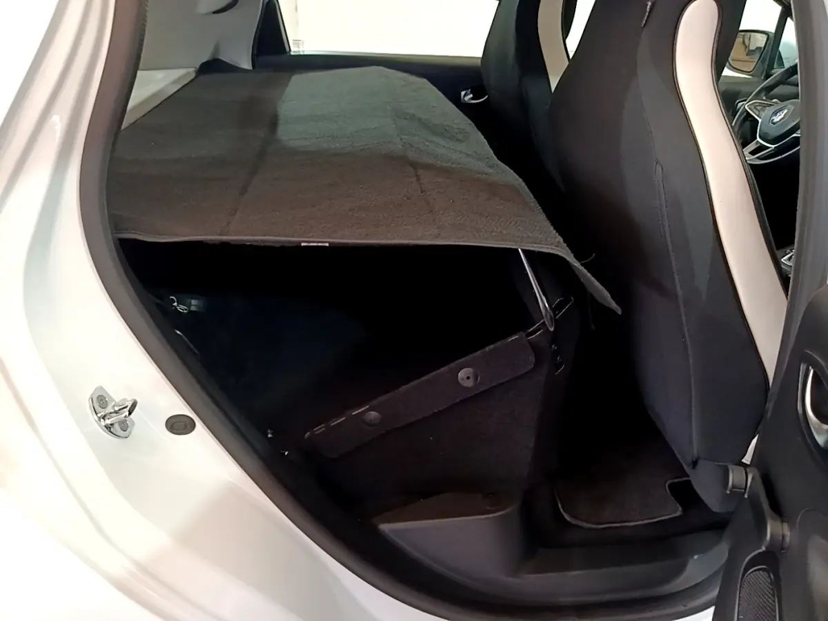 Vue intérieure côté gauche arrière de la Renault ZOE Business R110 blanche, montrant les sièges et le coffre partiellement couvert.
