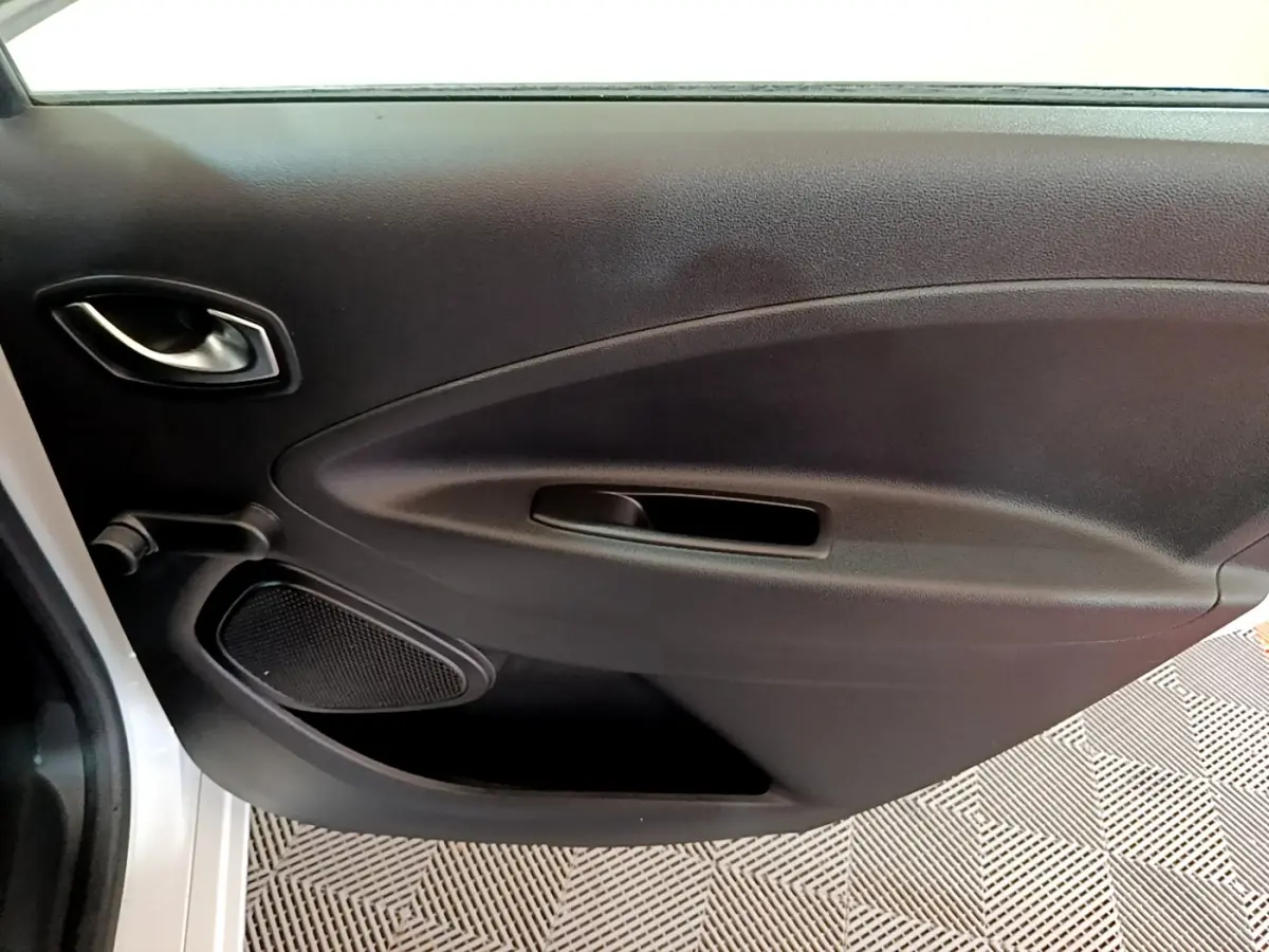 Vue intérieure sur la porte côté gauche noire de la Renault ZOE Business R110 blanche, avec poignée et haut-parleur intégrés.