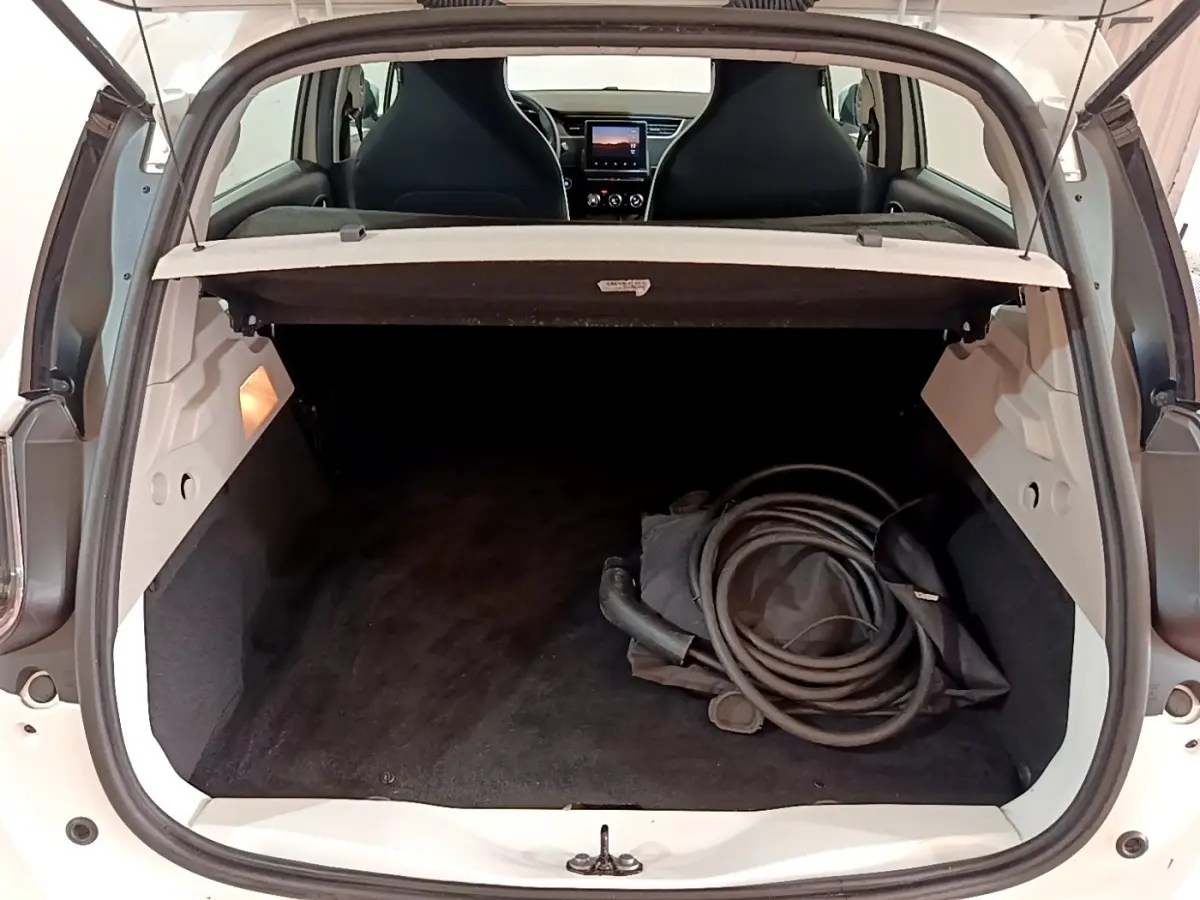 Coffre ouvert d'une Renault ZOE Business R110 blanche, vue arrière avec câble de recharge visible à l'intérieur.