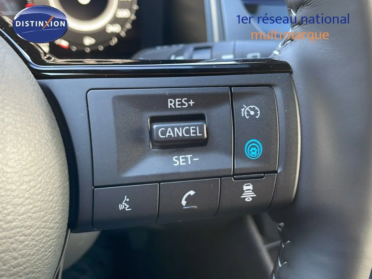 Gros plan sur les commandes au volant côté droit du Nissan Qashqai blanc nacré, avec boutons de régulateur de vitesse et assistance conduite.