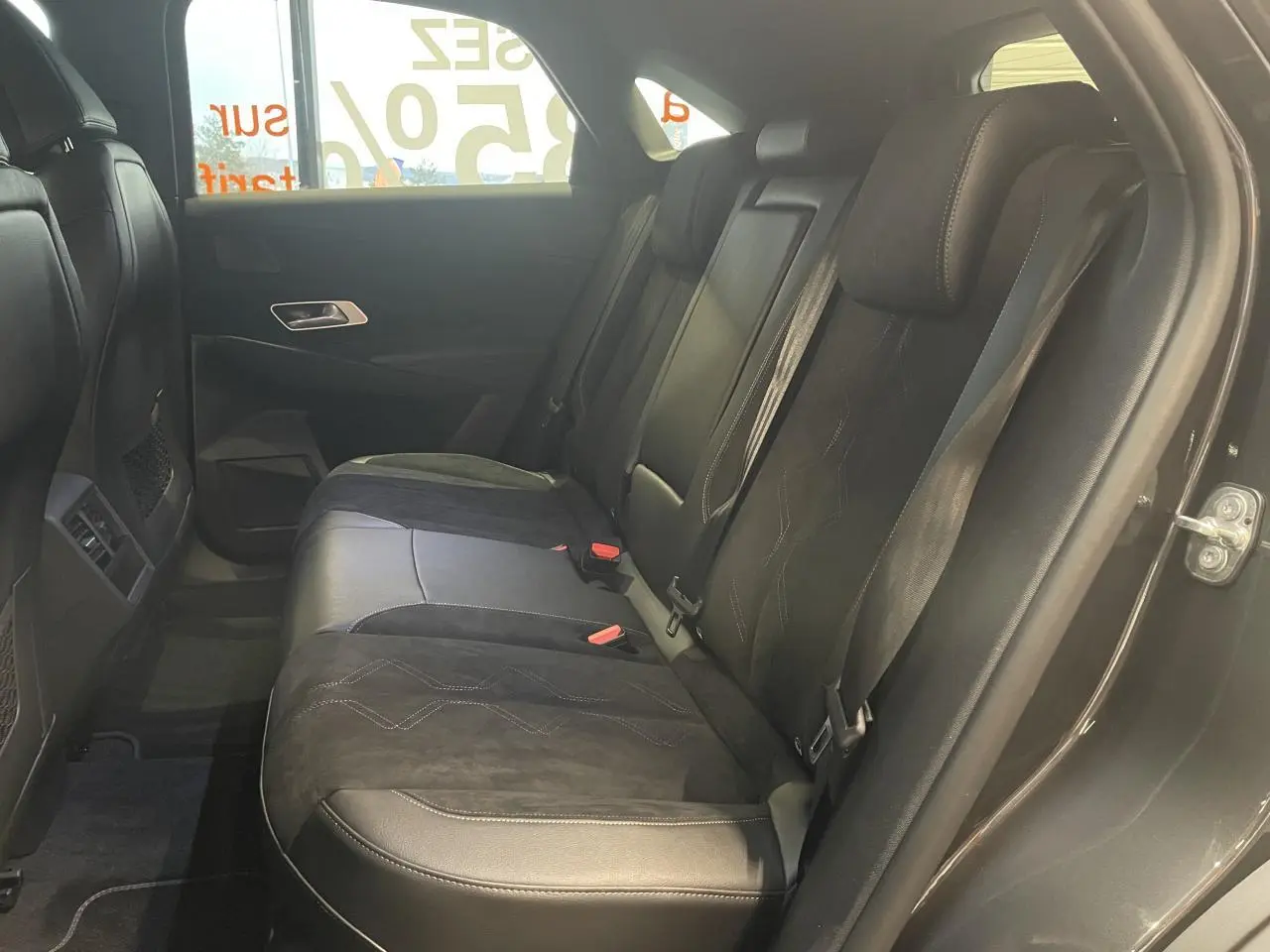 Vue latérale droite de la banquette arrière en Alcantara noir profond du DS7 Crossback gris titanium avec ceintures visibles.