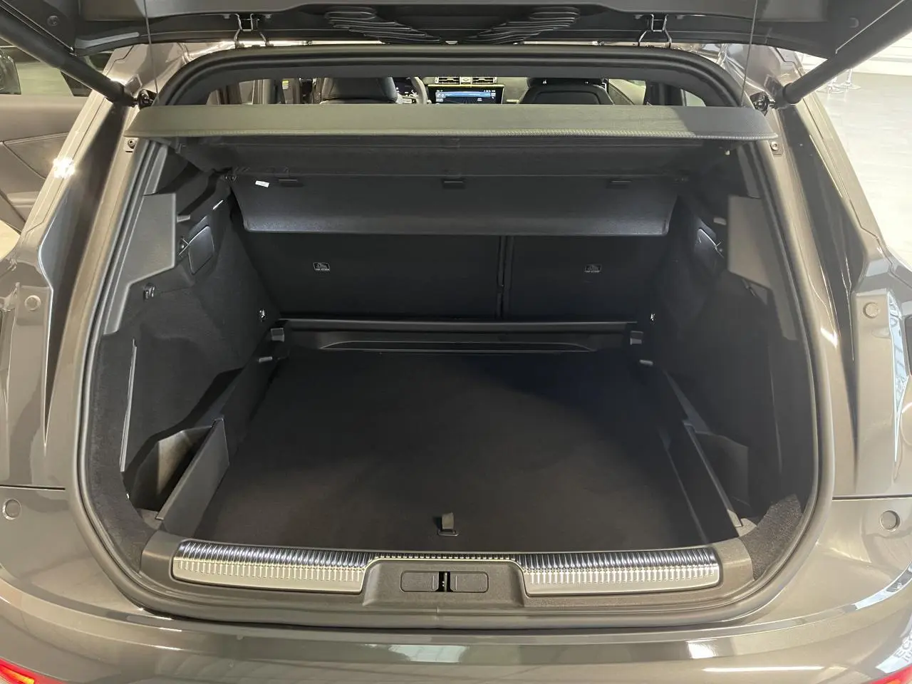 Coffre ouvert vu de l'arrière d'un DS7 Crossback gris titanium avec seuil de coffre chromé et intérieur noir.