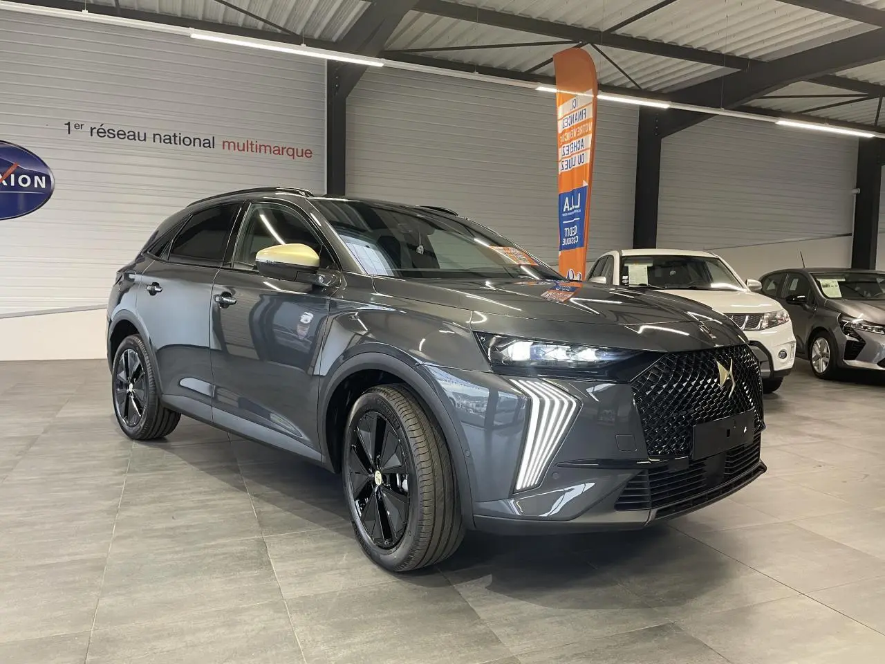 DS7 Crossback gris titanium en 3/4 avant droit avec calandre noire et feux LED distinctifs en showroom.