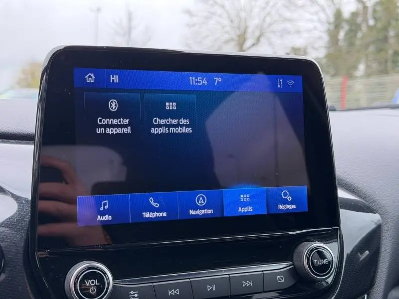 Écran tactile central du Ford Puma 2024 affichant les options audio, téléphone, navigation et réglages, intérieur noir.