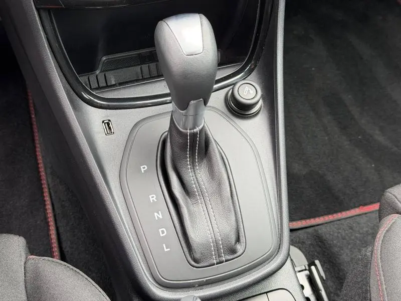 Gros plan sur la console centrale noire avec levier de vitesse automatique et surpiqûres blanches dans un Ford Puma gris Solar.