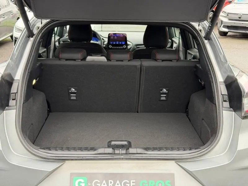 Coffre ouvert vu de l'arrière d'un Ford Puma gris Solar métallisé, banquette arrière noire avec surpiqûres rouges visible.