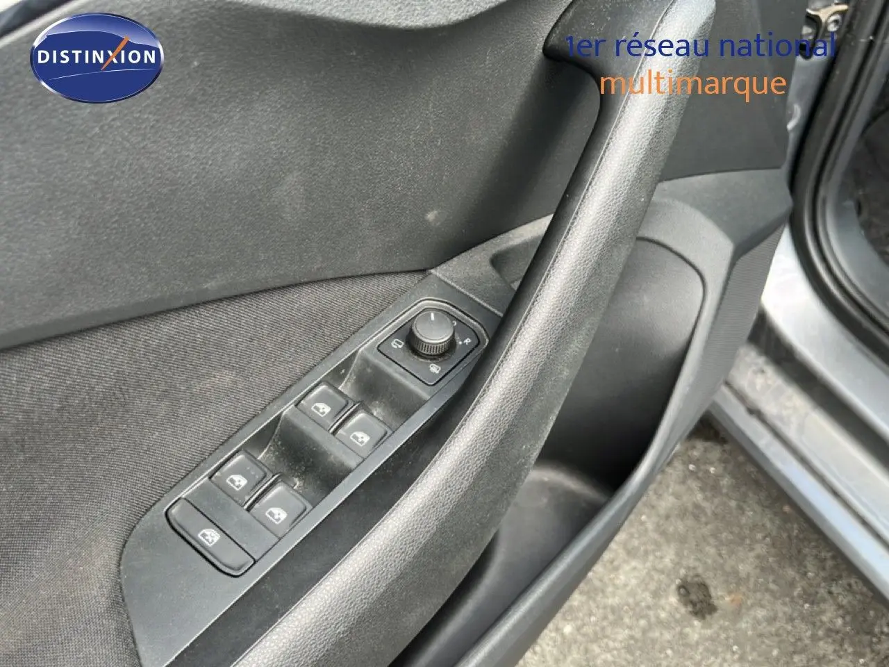 Gros plan sur la porte avant gauche d'une Skoda Scala gris magnétique, montrant les commandes des vitres électriques.