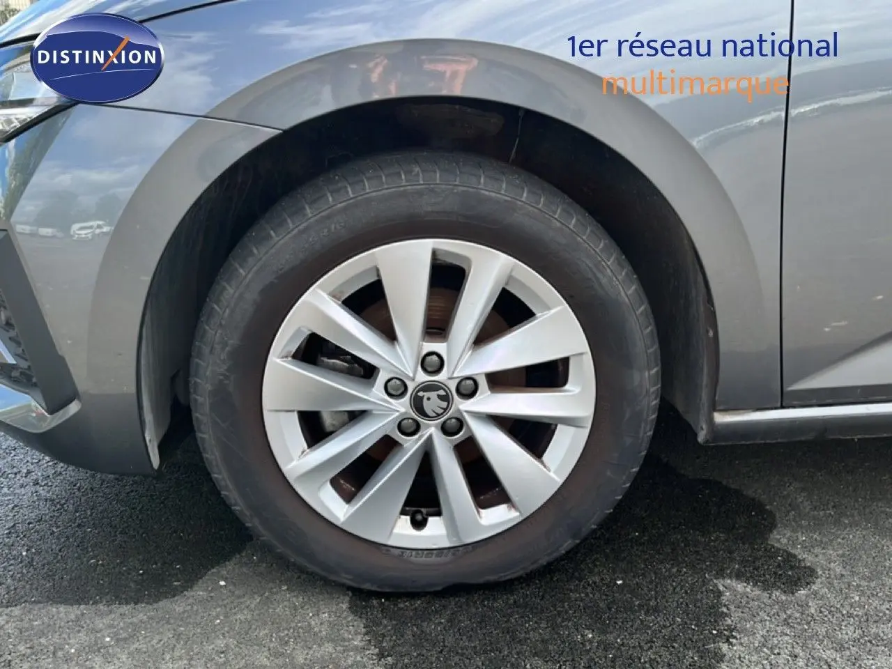 Gros plan sur la roue avant gauche d’une Skoda Scala gris magnétique métal avec jante alliage à dix branches.