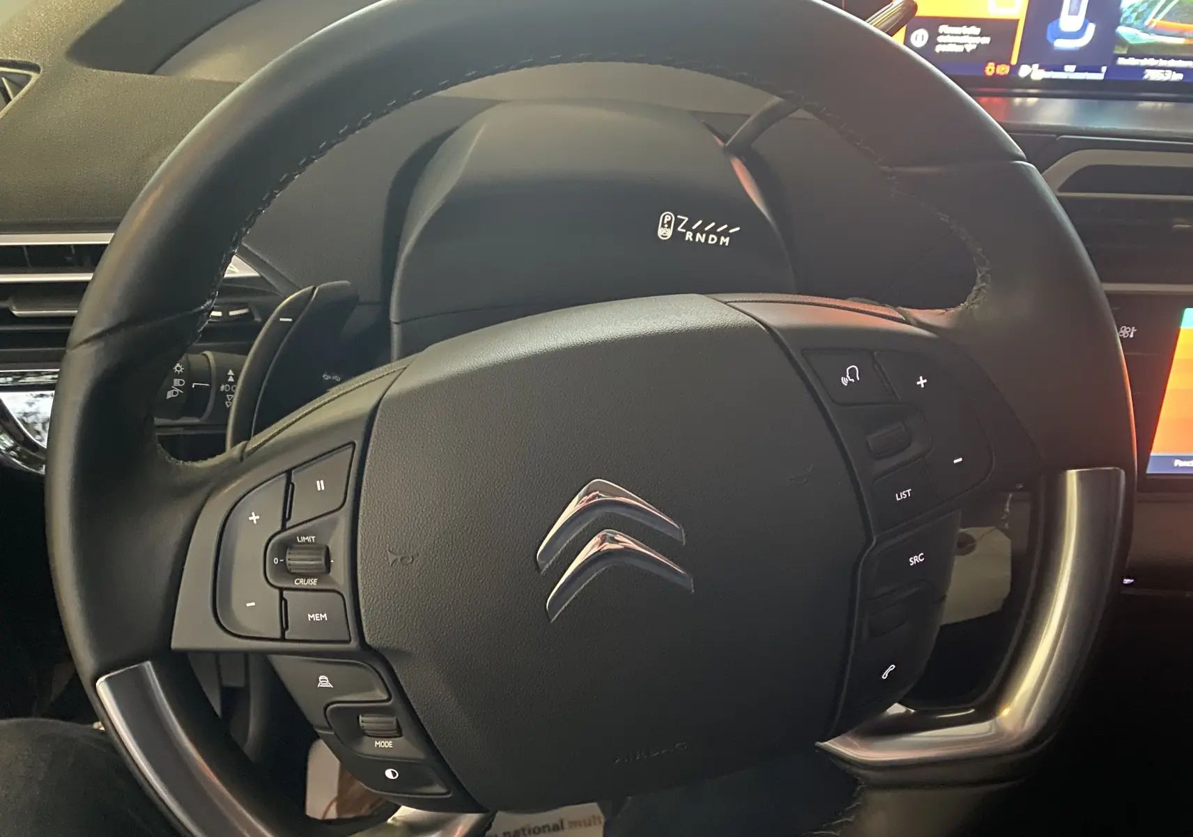 Volant noir de Citroën Grand C4 Spacetourer 2022, vue rapprochée centrée sur commandes intégrées et logo chromé.