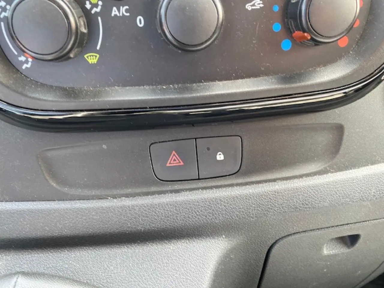 Gros plan sur les commandes de climatisation et les boutons de verrouillage et warning de l'Opel Vivaro blanc de 2018.