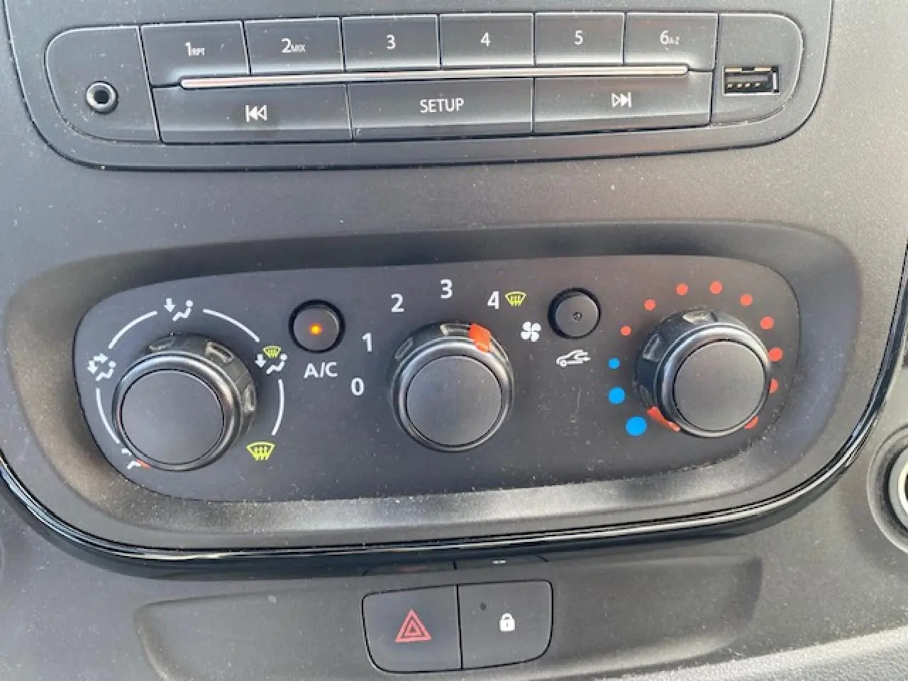 Gros plan sur les commandes de climatisation et audio du tableau de bord d'un Opel Vivaro blanc de 2018.